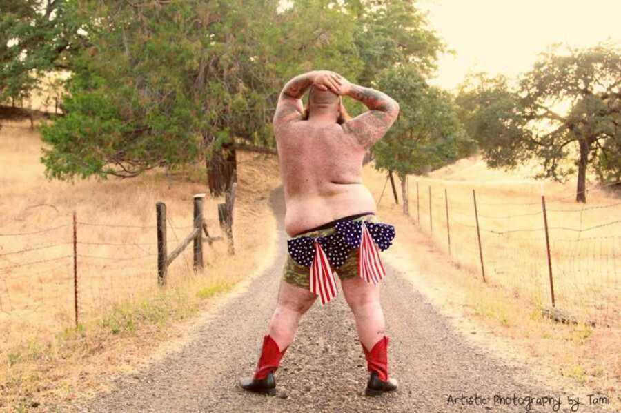 Shirtless man posing on dirt road with cowboy boots on 