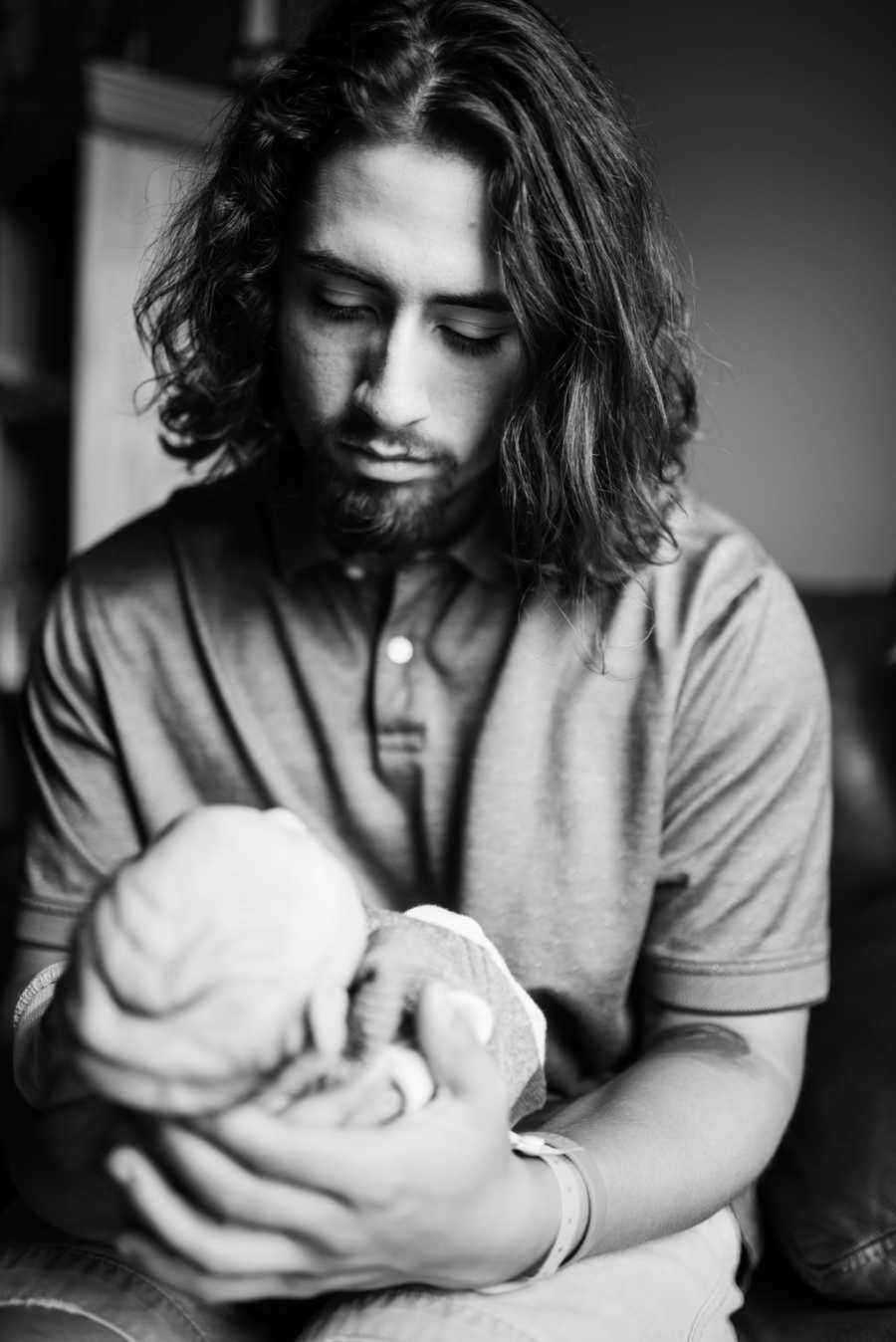 Dad looking at newborn son in hands