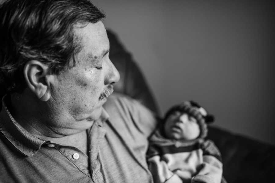 Grandpa gazing at newborn grandson in his arms