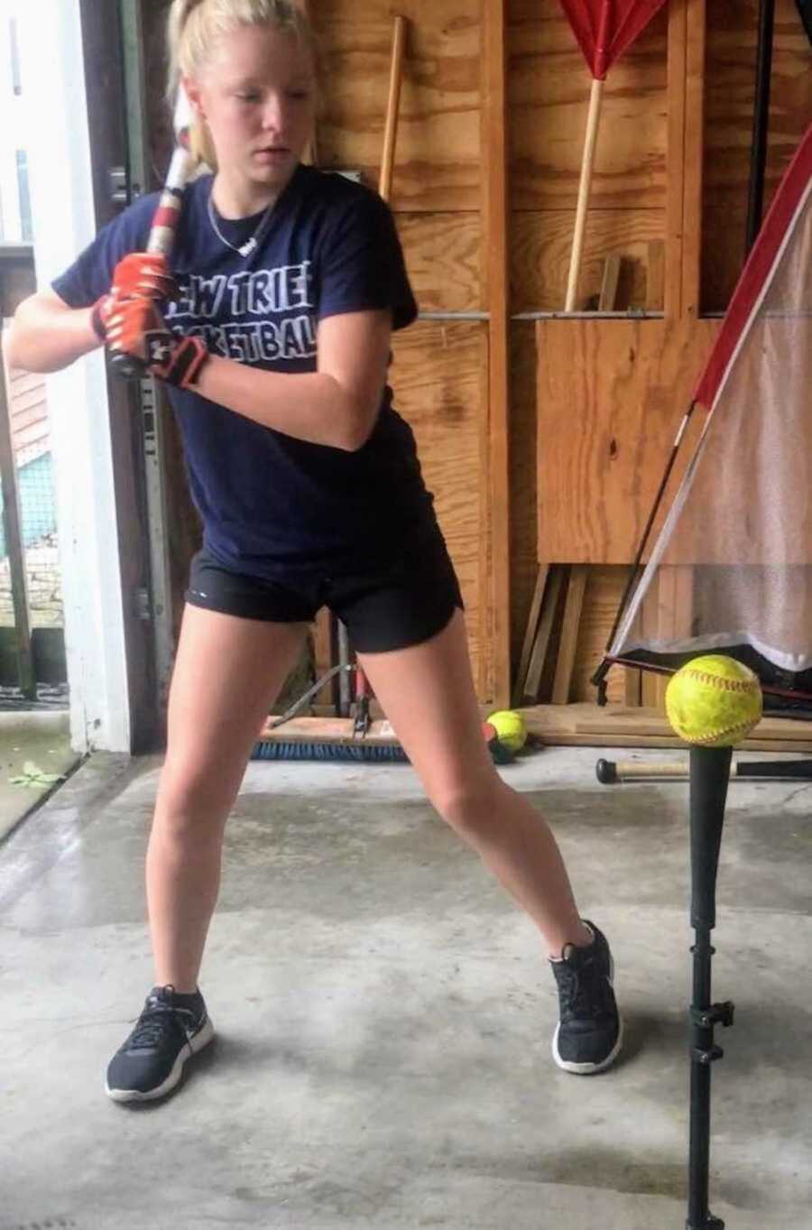 Teen girl swinging baseball bat in garage