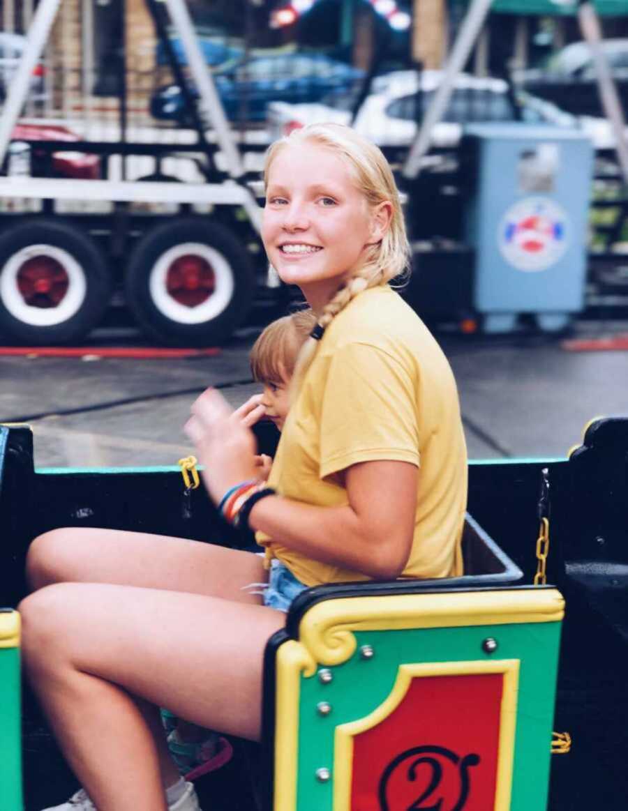 Teen girl sitting next to little boy on rollercoaster