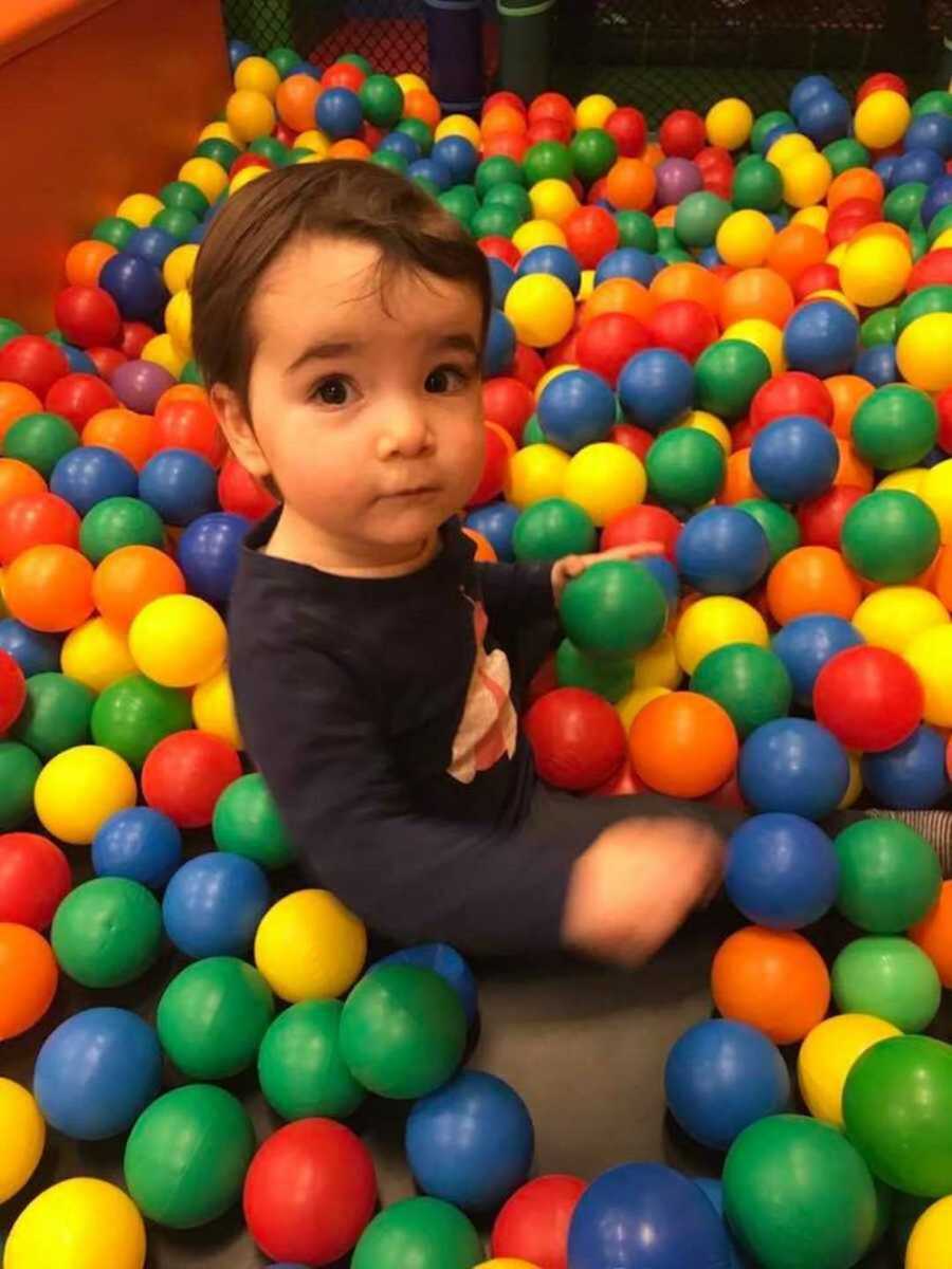 little boy sitting in ball pit