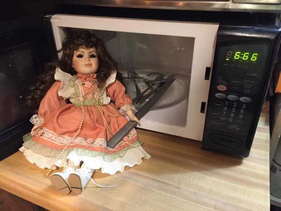creepy doll holding knife by microwave