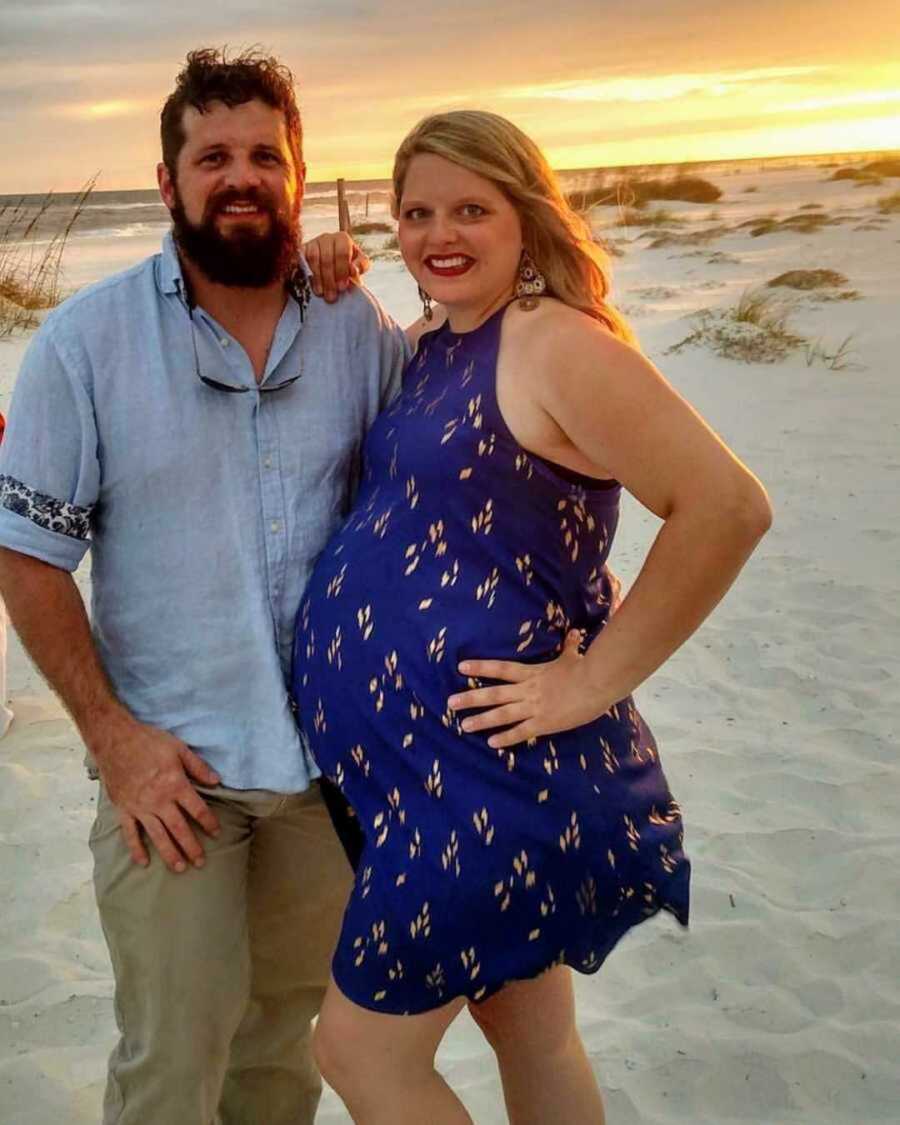 Pregnant woman and husband smiling on beach