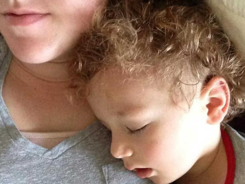Toddler with curly hair sleeping on mom with mouth open