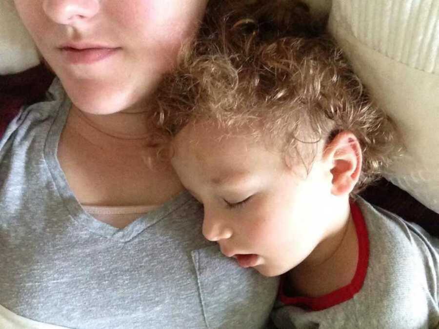 Toddler with curly hair sleeping on mom's chest