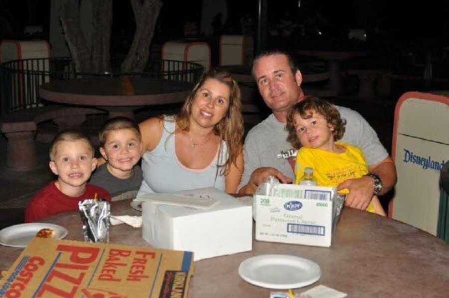 Family of five eating pizza together at table