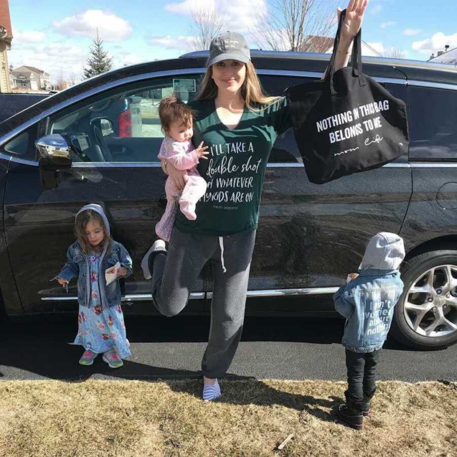 mom poses with three kids in front of car