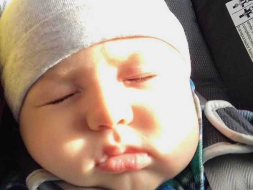 Infant in gray hat sleeping in carseat