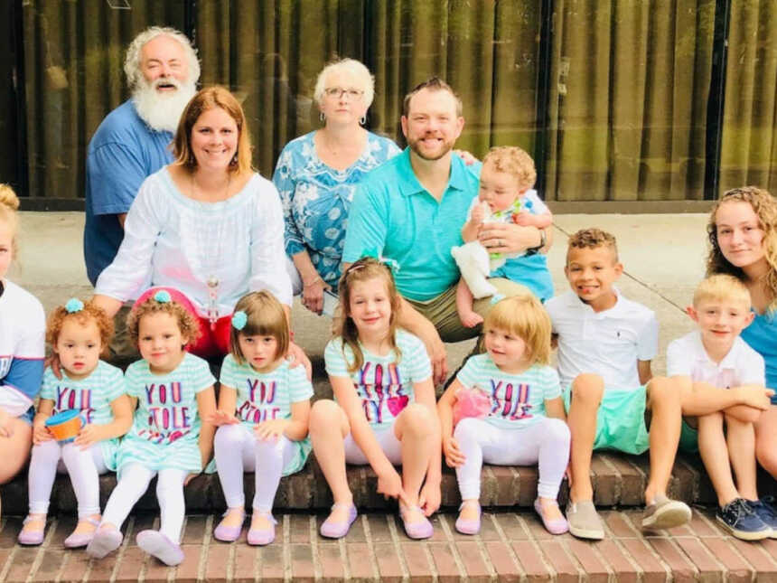 Husband and wife sit beside their biological kids and eight adopted children beside elderly couple