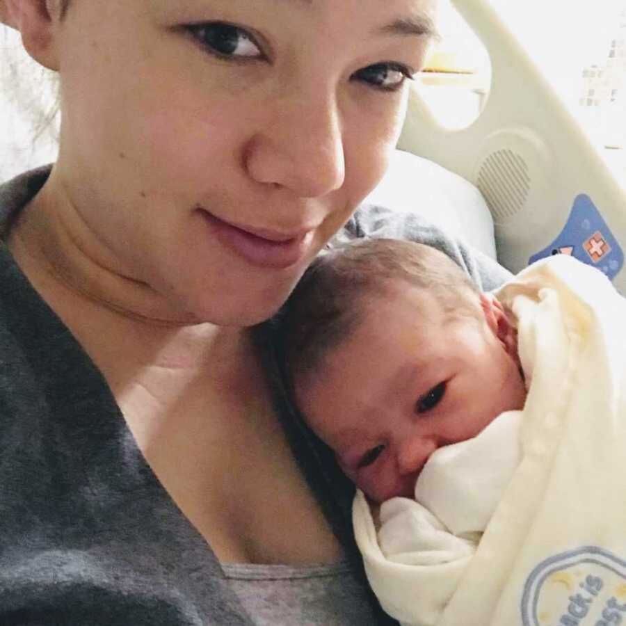 Mom embracing newborn in hospital bed