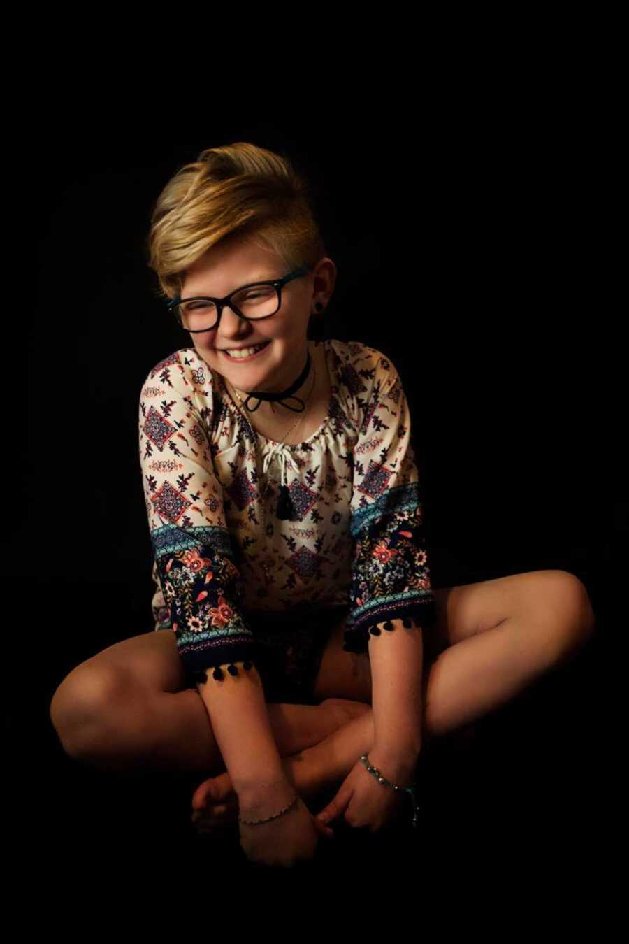 Girl with short blonde hair smiling on floor