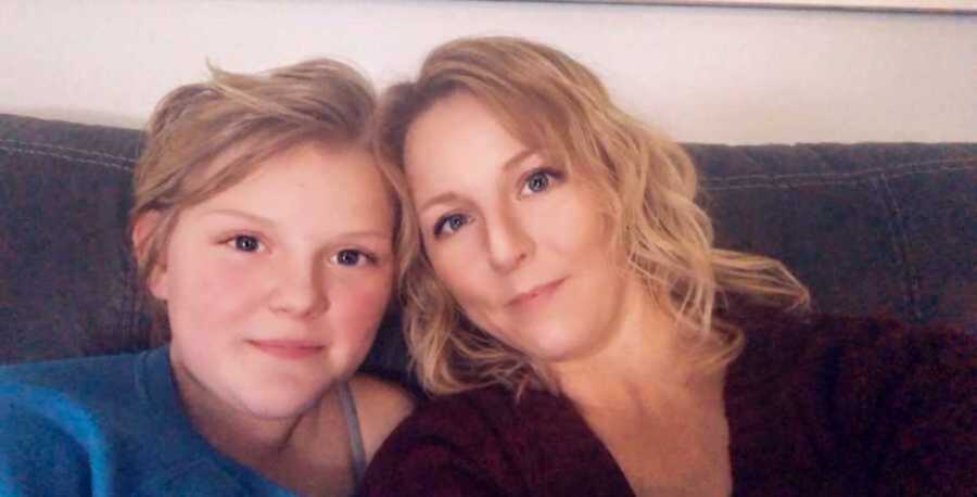 Selfie of mom and daughter sitting on gray couch