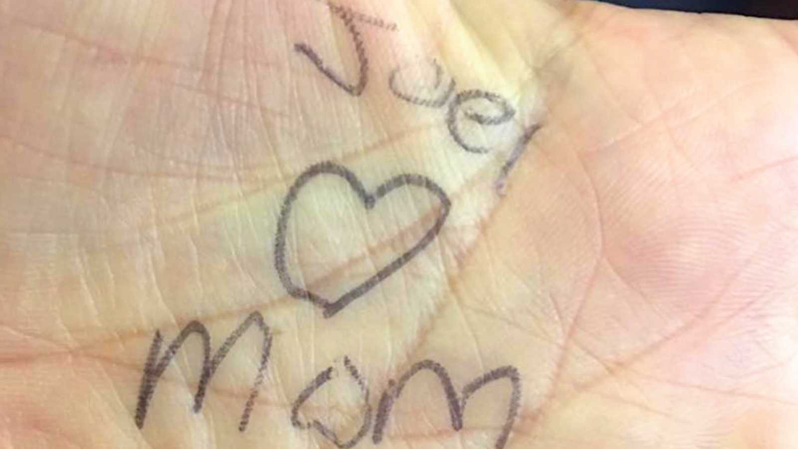 hand with "joel loves mom" writen on palm in pen