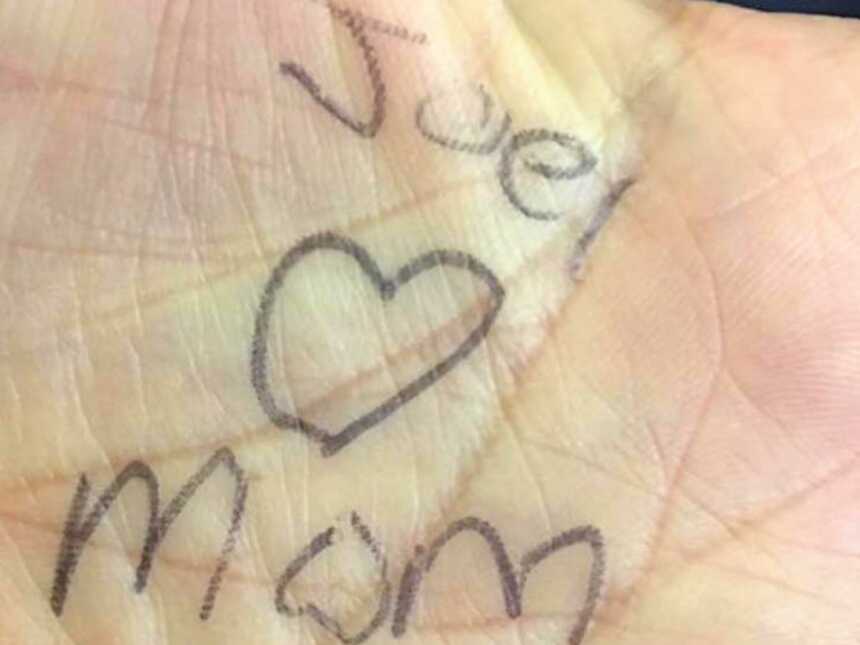 hand with "joel loves mom" writen on palm in pen