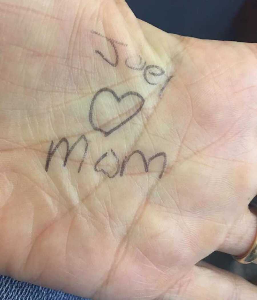hand with "joel loves mom" written in pen