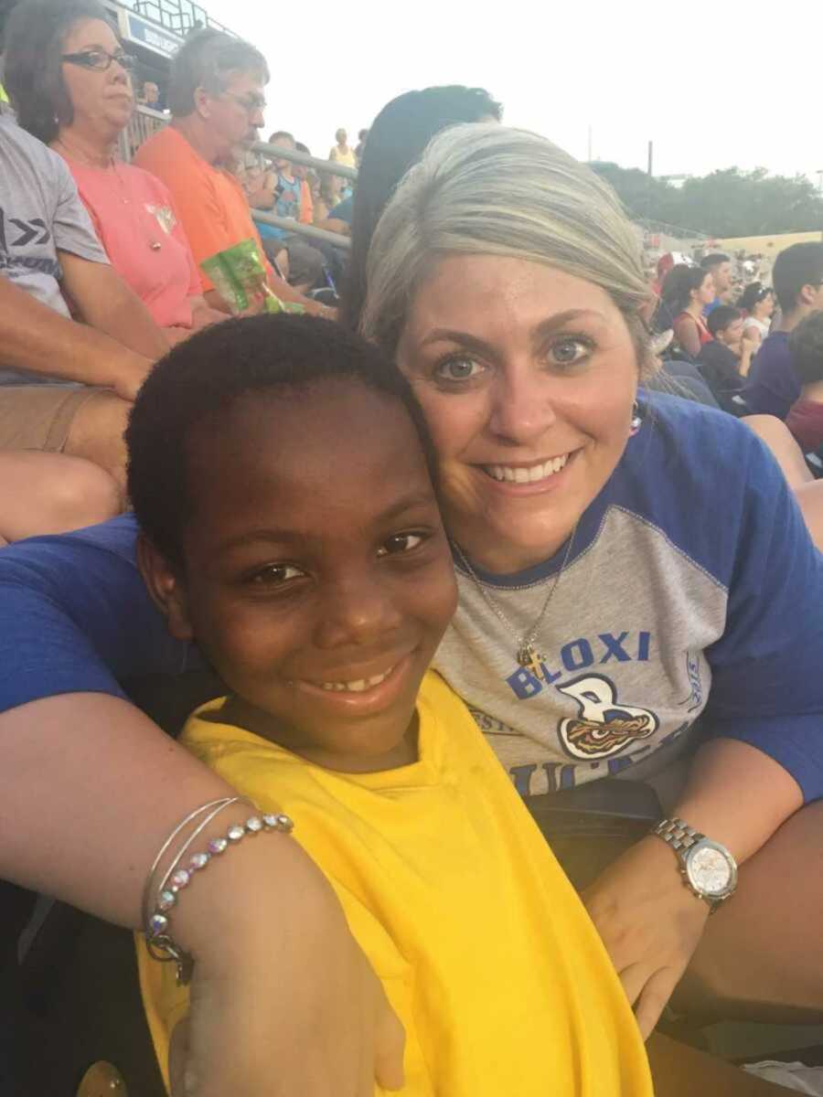 Foster mom smiling with little boy on bleachers