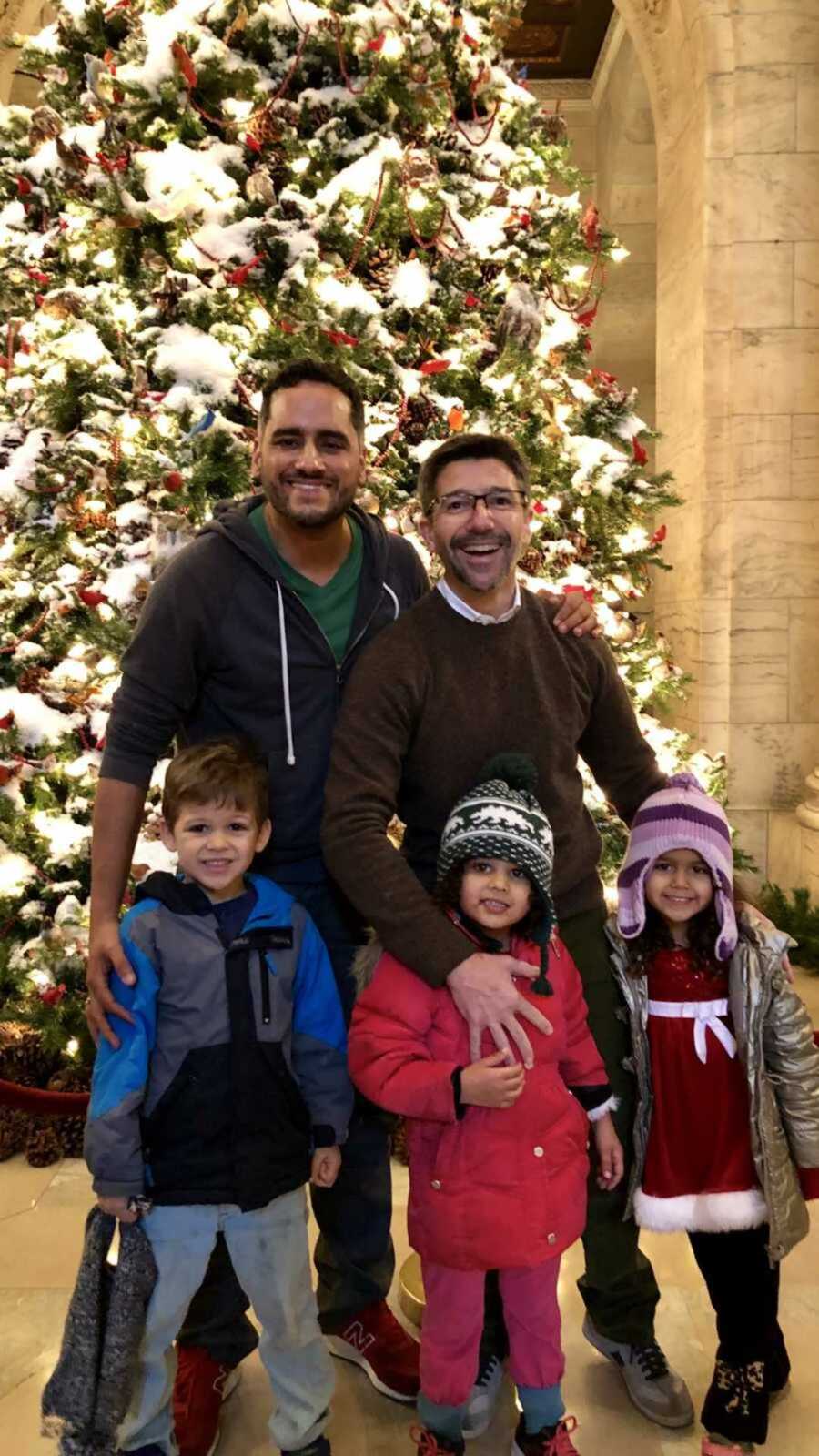 Gay couple with their children during Christmas time in front of a decorated tree