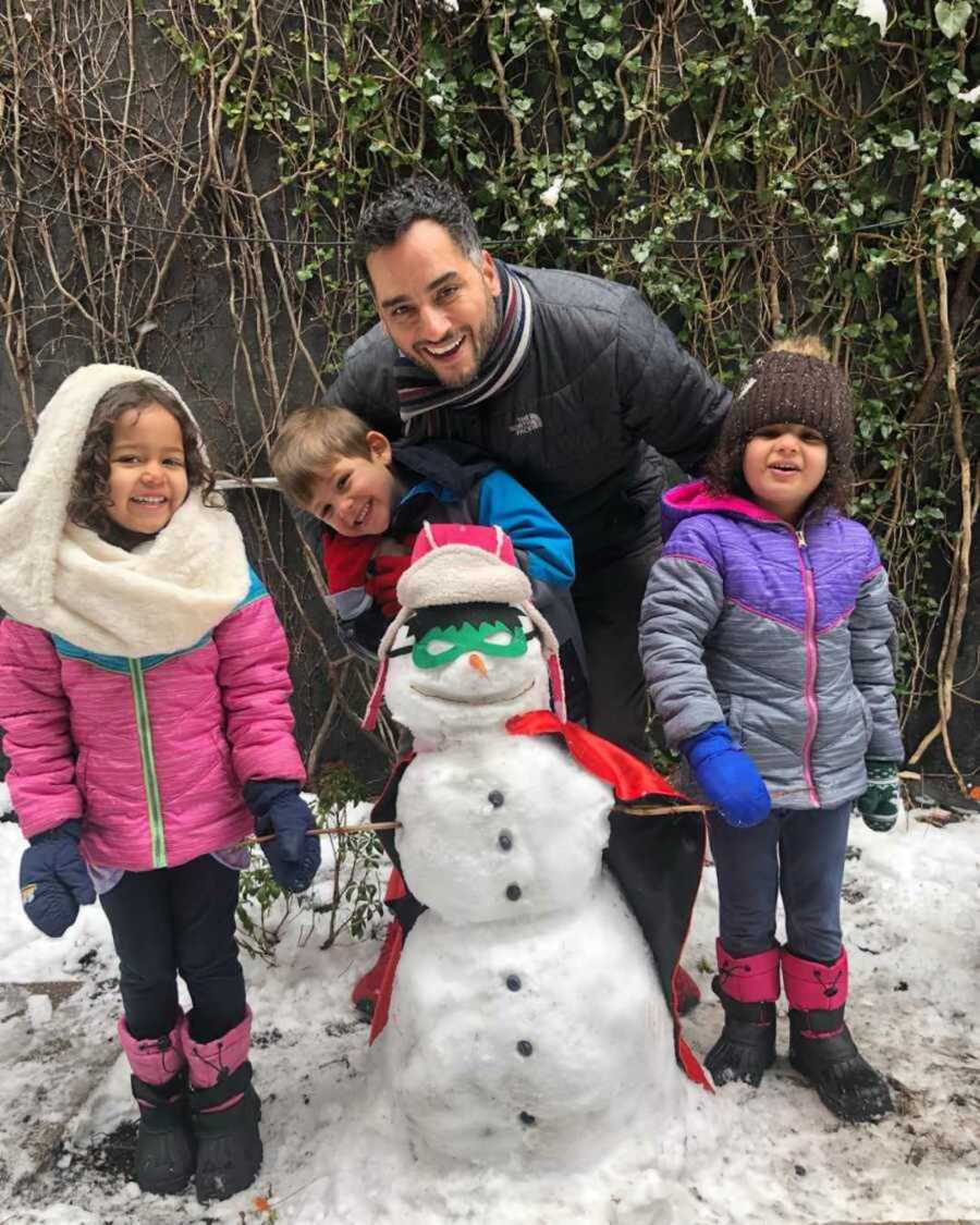 Single dad with his children in snow gear who made a snowman