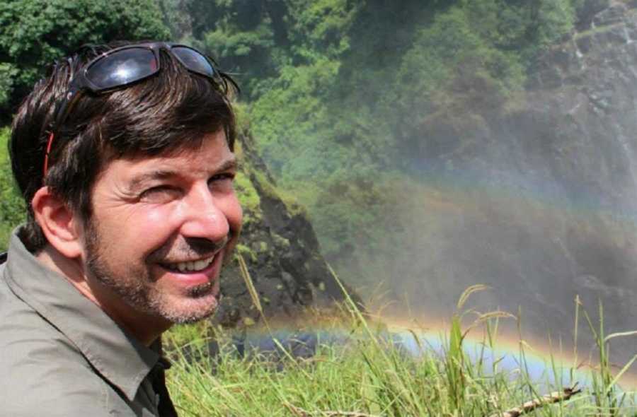 Smiling dad outside in front of a rainbow 