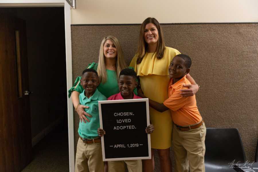 Adoptive mom smiles with three adopted sons in courtroom building
