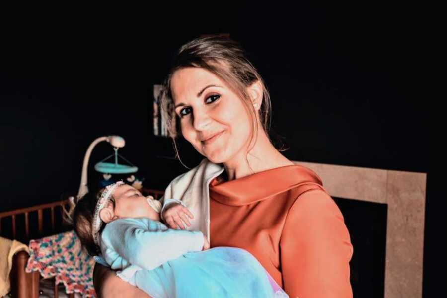 mother holds her newborn baby daughter close, smiling softly