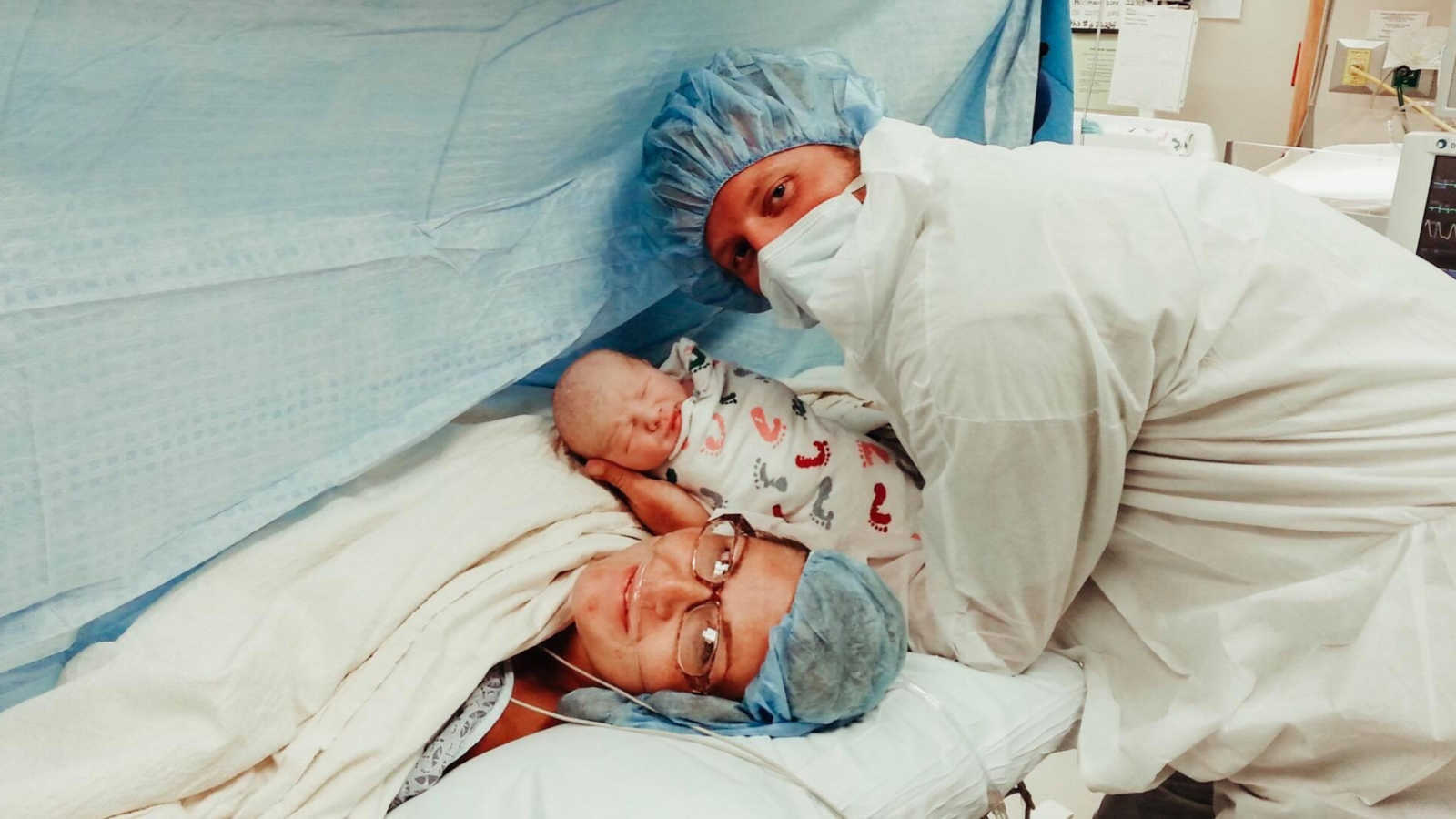 new father holds newborn baby by mother after she gives birth