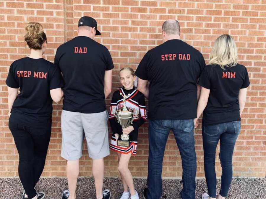 daughter in cheerleader uniform posing with stepparents