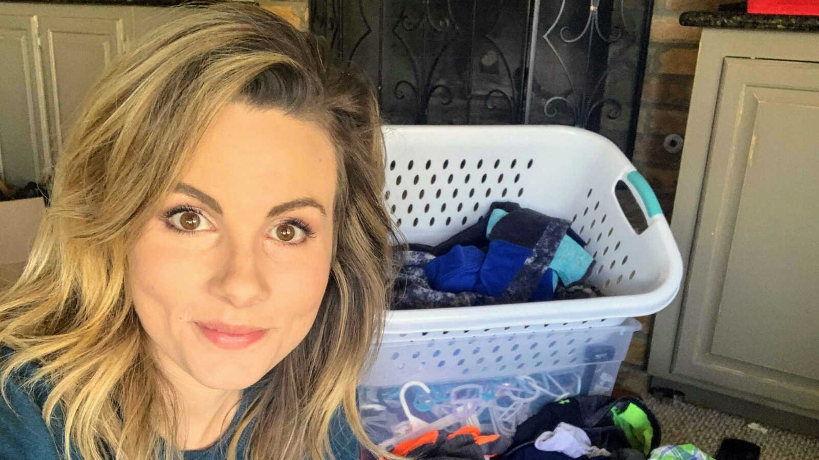 Mother smiling amongst pile of clothes and laundry basket