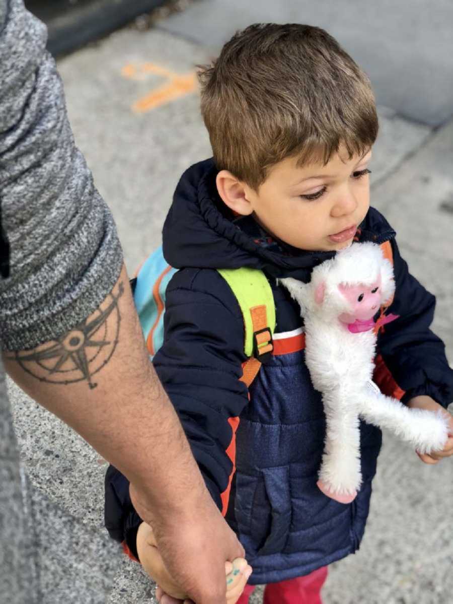 Little boy with backpack on holding his dads hand