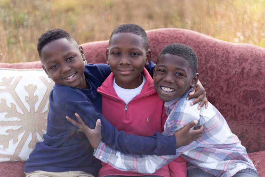 Three brothers hugging on red couch
