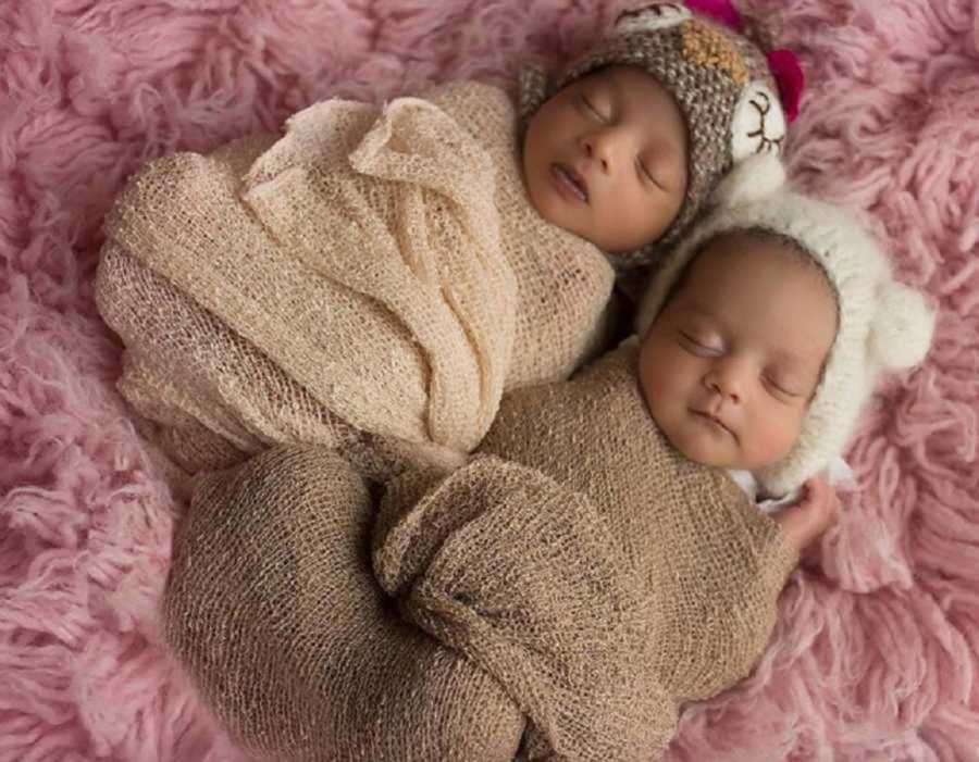 Newborn twins sleeping as they are wrapped in blankets