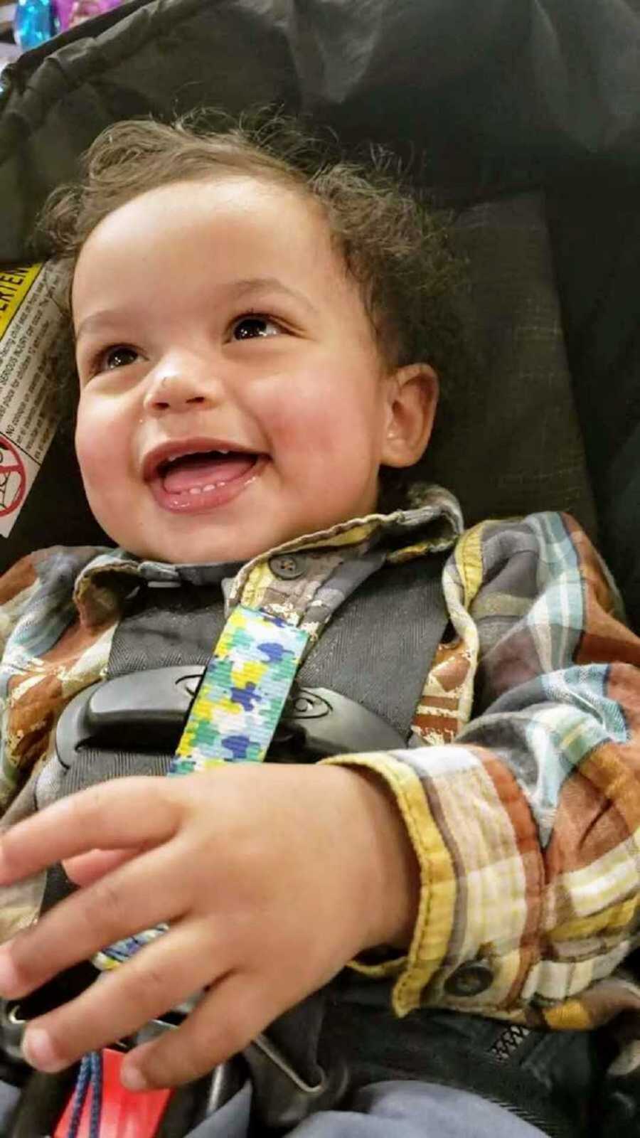 1 year old boy smiling in car seat