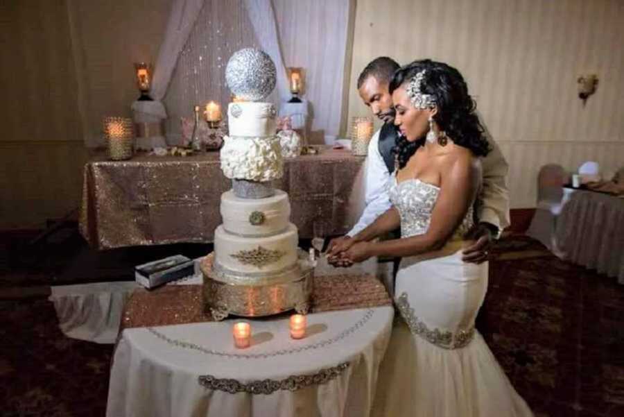Bride and groom cutting white five-layer wedding cake