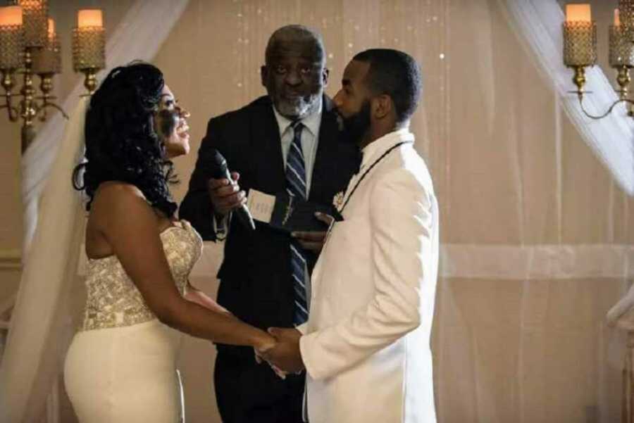 Bride smiling at groom in front of pastor