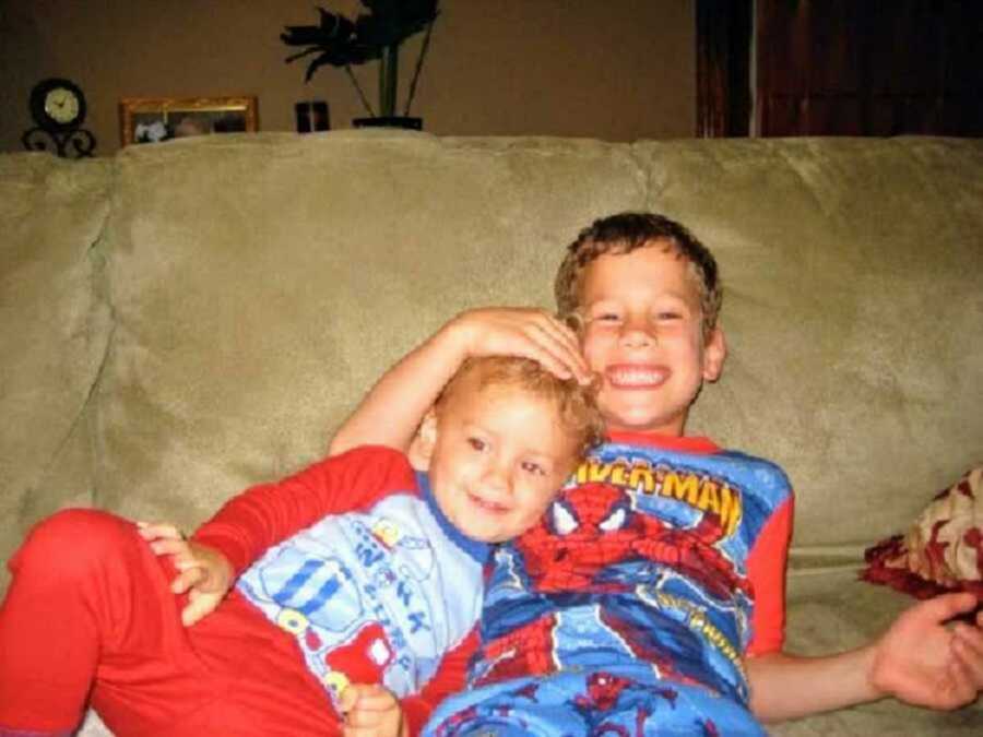 brothers sit on a couch together wearing their pajamas