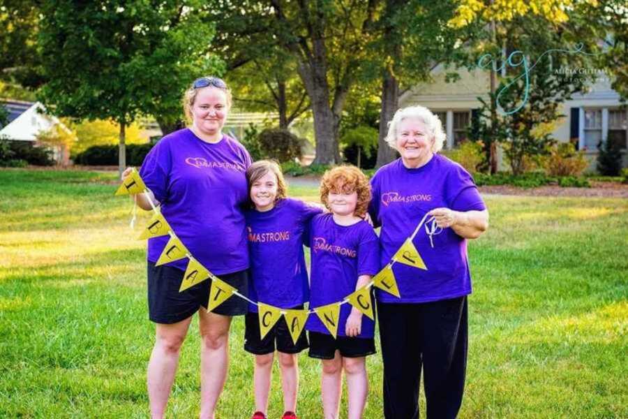 family stands with "I beat cancer" sign