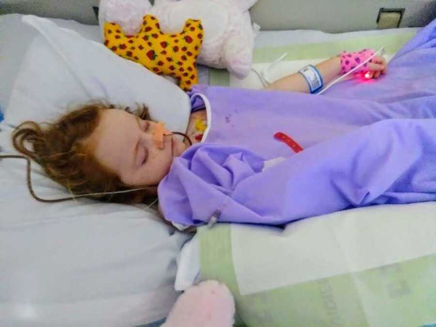 girl with cancerous tumor lays in hospital bed