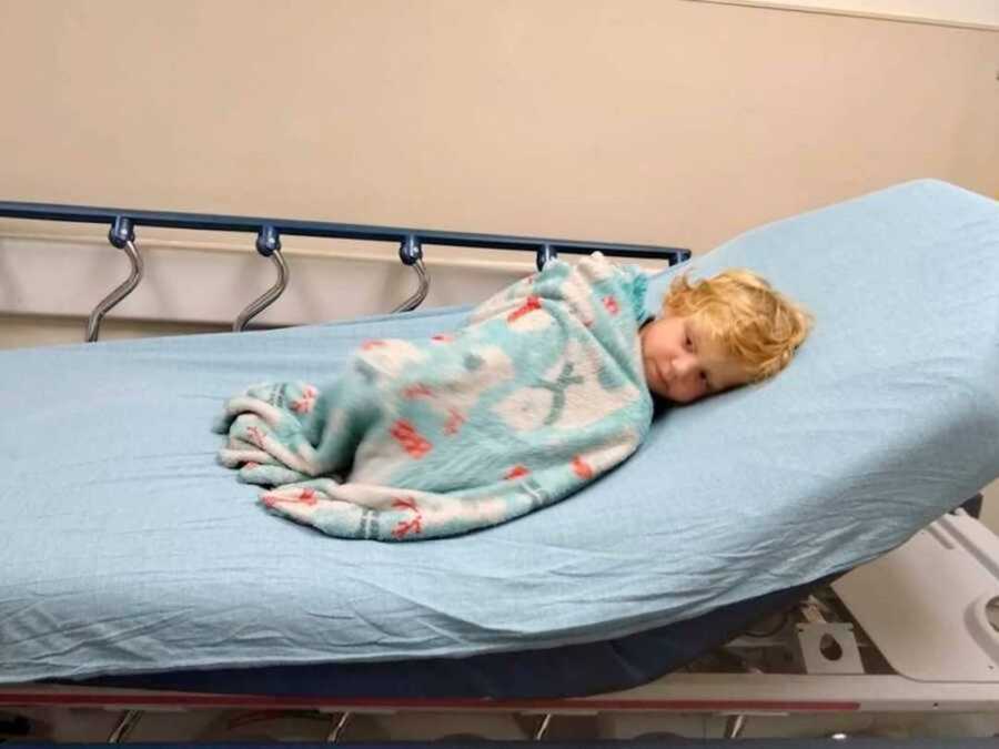 Blonde boy lying in hospital bed
