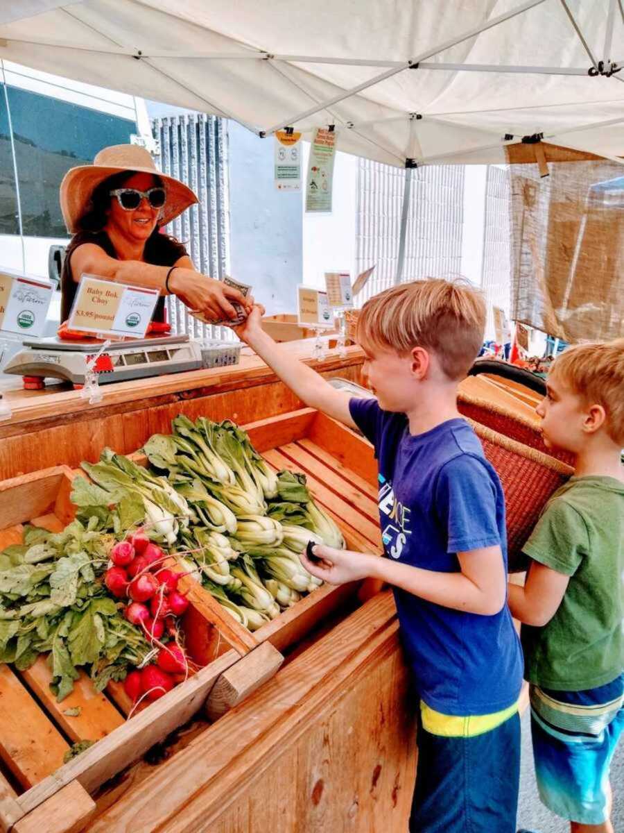 children stand by farmers market produce