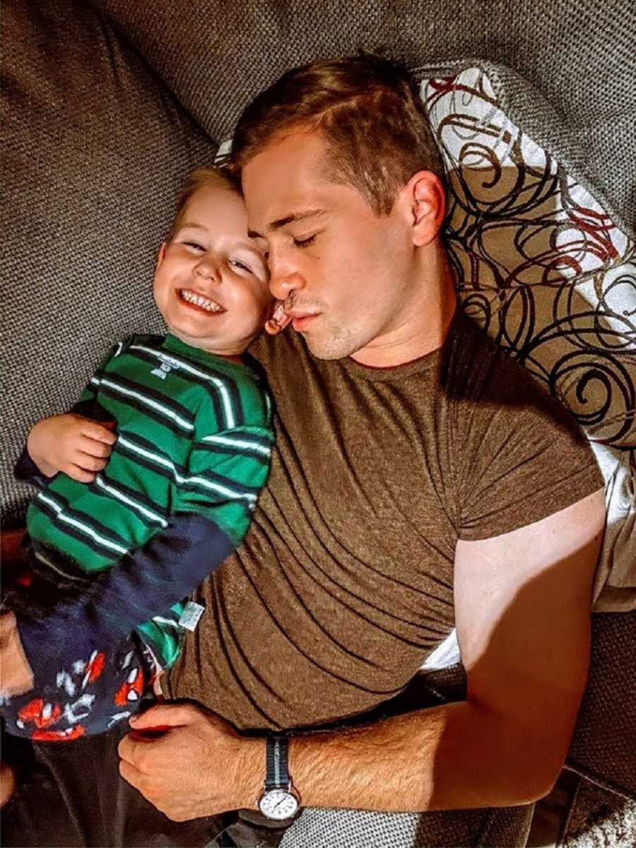 dad laying down holding smiling son