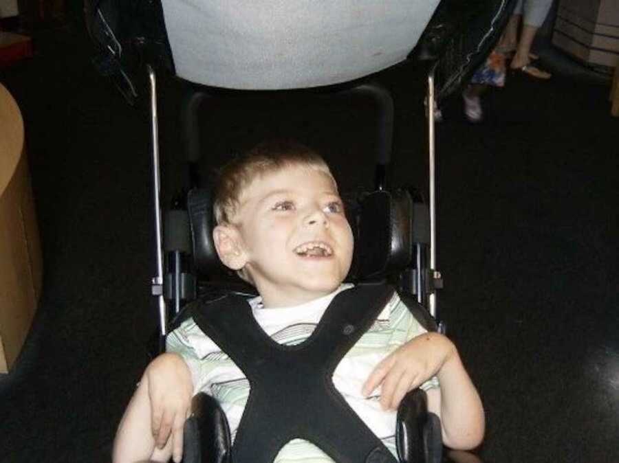 Smiling disabled child in his stroller 