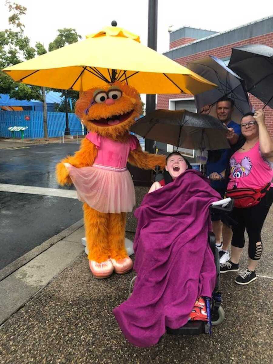 Family of disabled child standing next to an Elmo character