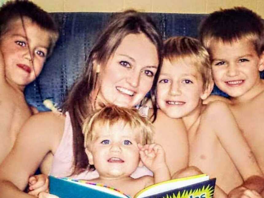 mother sits on chair reading with her four sons sitting around her