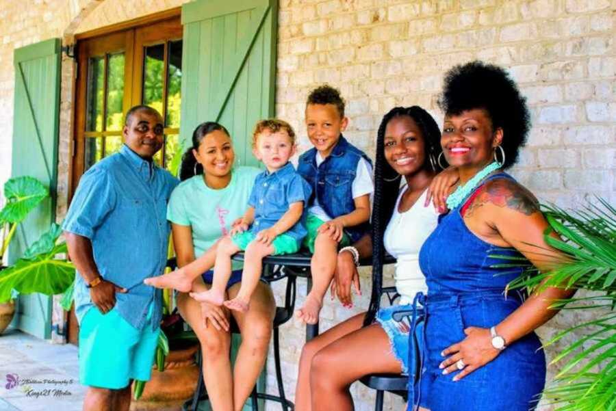 Adoptive family smiling outside house