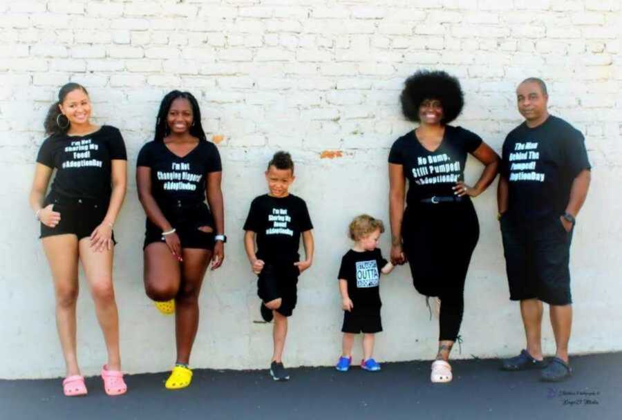 Adoptive family of 6 posing against white brick wall