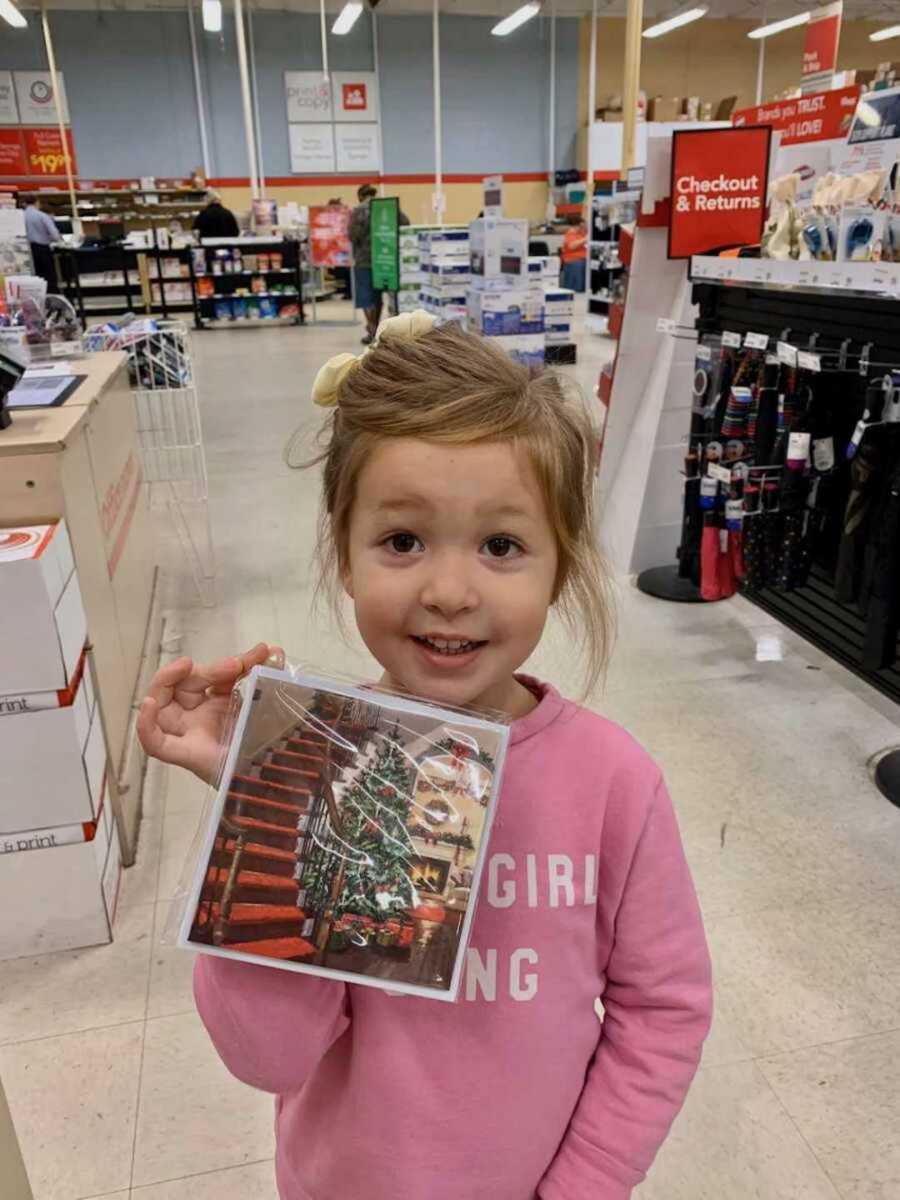 girl smiling holding christmas card in store