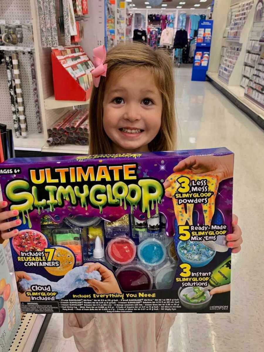 girl smiling holding slime-making kit in store
