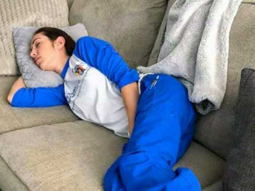 Nurse napping on couch in blue scrubs