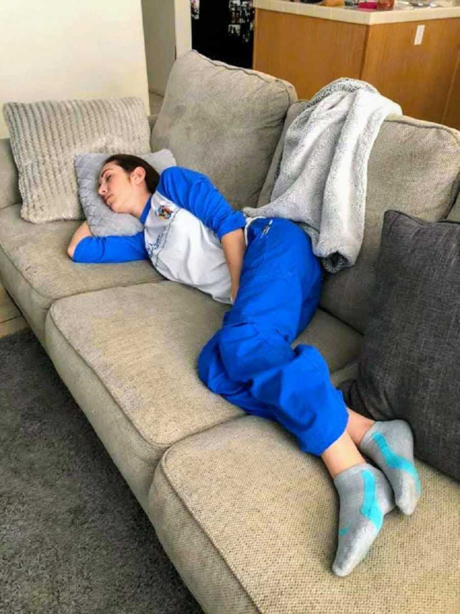 Nurse sleeping on couch wearing blue scrubs